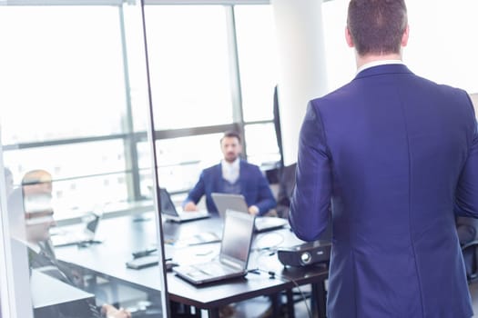 Business man making a presentation at office. Business executive delivering a presentation to his colleagues during meeting or in-house business training, explaining business plans to his employees.