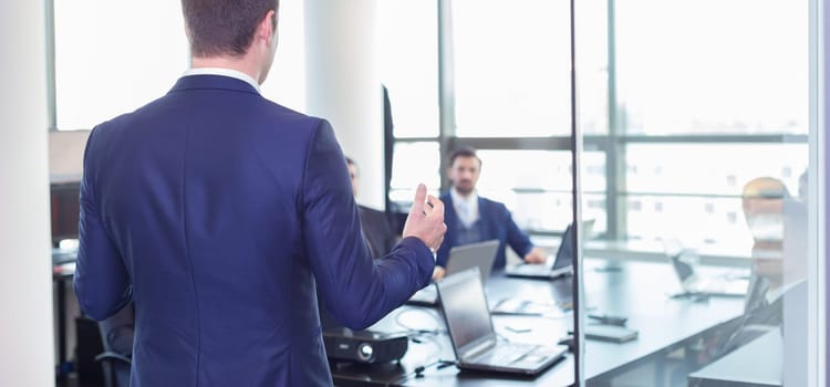 Business man making a presentation at office. Business executive delivering a presentation to his colleagues during meeting or in-house business training, explaining business plans to his employees.