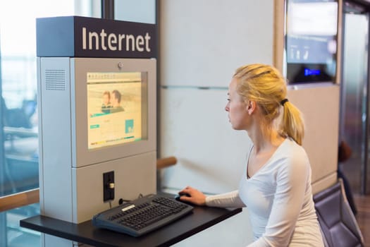 Young caucasian woman using comupter with public internet access point on airport.