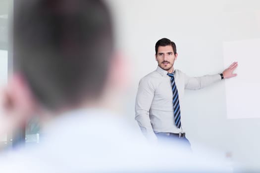 Business man making a presentation at office. Business executive delivering a presentation to his colleagues during meeting or in-house business training, explaining business plans to his employees.