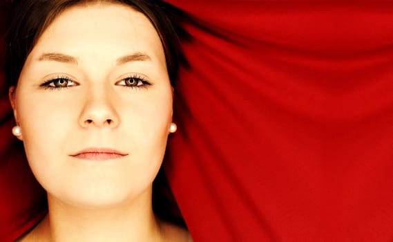 Beauty portrait of a beautiful teenage woman in front of a red curtain