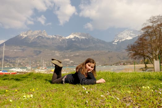 a pretty preteen is lying in the green grass, in the spring