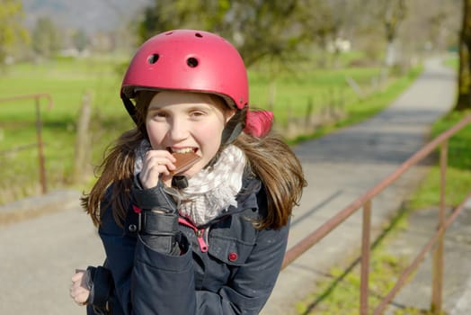 pretty preteen with roller skate helmet, eat a cake