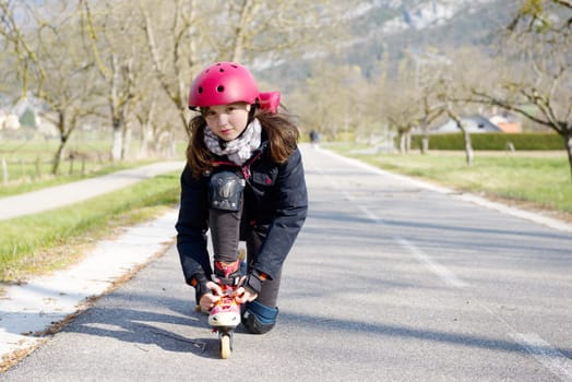 pretty preteen girl on roller skates in helmet at a track