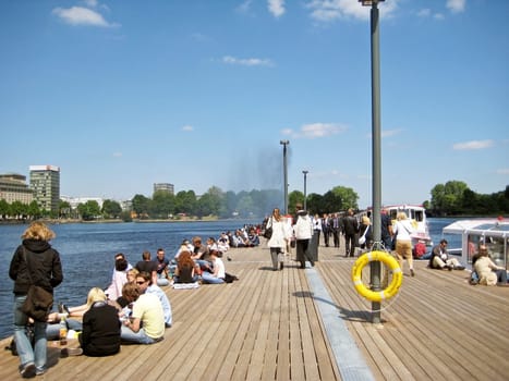 Hamburg, Germany - May 22, 2008: Lake Binnenalster - pier with young people relaxing - excursion boats starting from here for trips on the Alster