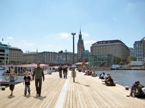 Hamburg, Germany - May 22, 2008: Pier of Lake Binnenalster - people relaxing - excursion boats starting from here for trips on the Alster. Historic town hall in the background