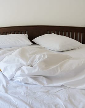 Morning view of an unmade bed in white bedroom