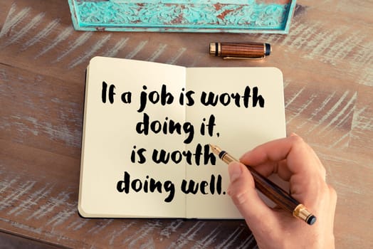 Retro effect and toned image of a woman hand writing on a notebook. Handwritten quote If a job is worth doing it is worth doing well as inspirational concept image