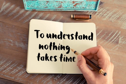 Retro effect and toned image of a woman hand writing on a notebook. Handwritten quote To understand nothing takes time as inspirational concept image