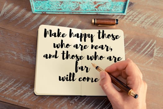 Retro effect and toned image of a woman hand writing on a notebook. Handwritten quote Make happy those who are near, and those who are far will come as inspirational concept image
