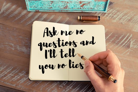 Retro effect and toned image of a woman hand writing on a notebook. Handwritten quote Ask me no questions and I’ll tell you no lies as inspirational concept image
