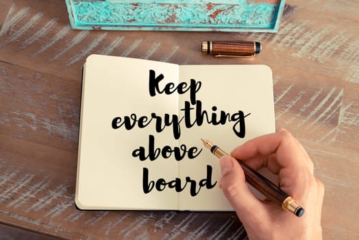 Retro effect and toned image of a woman hand writing on a notebook. Handwritten quote Keep everything above board as inspirational concept image