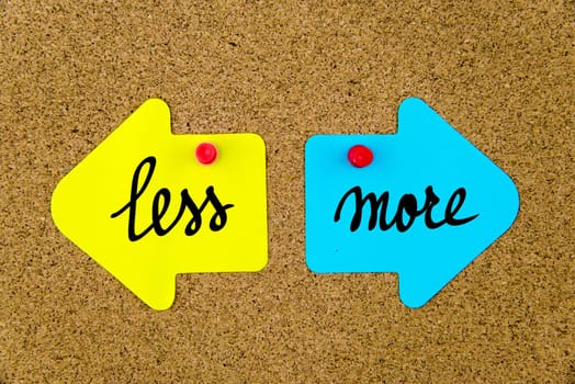 Blank yellow and blue paper notes in shape of opposite arrows pinned on cork board with thumbtacks, copy space available