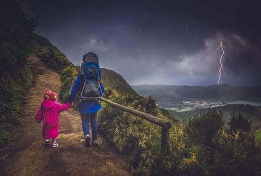 Mother and her children walking on a mountain trail in stormy and rainy weather, Sao Miguel, Azores, Portugal
