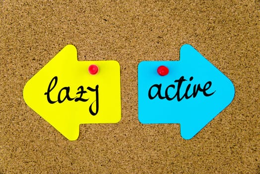 Blank yellow and blue paper notes in shape of opposite arrows pinned on cork board with thumbtacks, copy space available