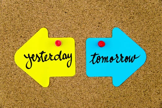 Blank yellow and blue paper notes in shape of opposite arrows pinned on cork board with thumbtacks, copy space available