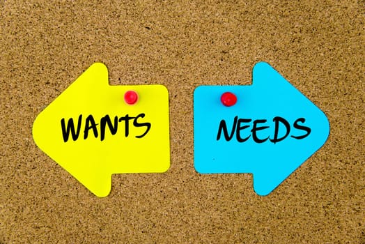 Blank yellow and blue paper notes in shape of opposite arrows pinned on cork board with thumbtacks, copy space available