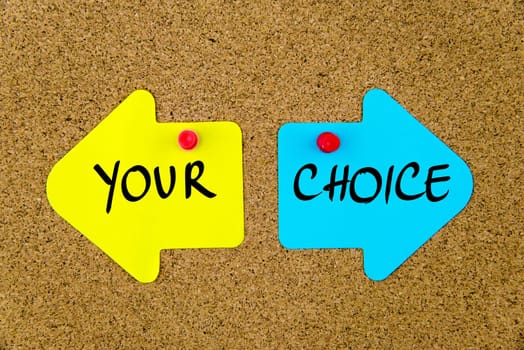 Blank yellow and blue paper notes in shape of opposite arrows pinned on cork board with thumbtacks, copy space available