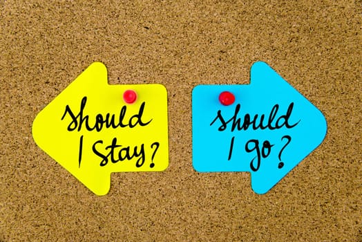 Blank yellow and blue paper notes in shape of opposite arrows pinned on cork board with thumbtacks, copy space available