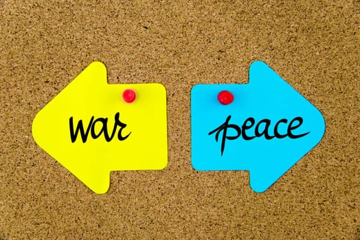 Blank yellow and blue paper notes in shape of opposite arrows pinned on cork board with thumbtacks, copy space available