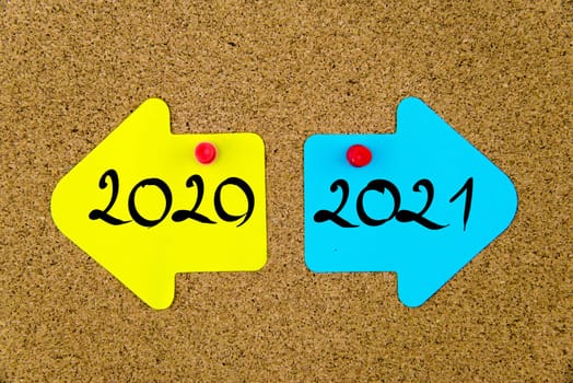 Blank yellow and blue paper notes in shape of opposite arrows pinned on cork board with thumbtacks, copy space available