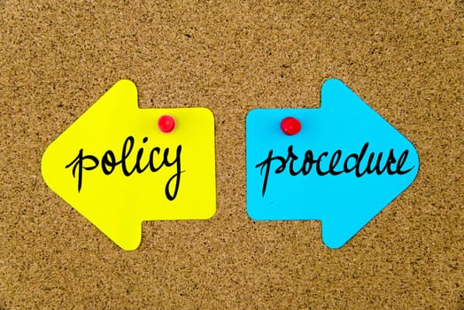 Blank yellow and blue paper notes in shape of opposite arrows pinned on cork board with thumbtacks, copy space available
