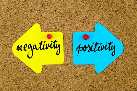Blank yellow and blue paper notes in shape of opposite arrows pinned on cork board with thumbtacks, copy space available