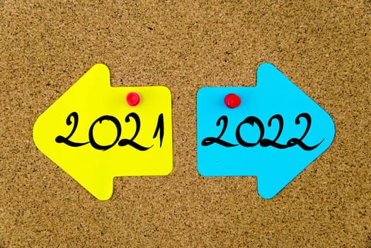 Blank yellow and blue paper notes in shape of opposite arrows pinned on cork board with thumbtacks, copy space available