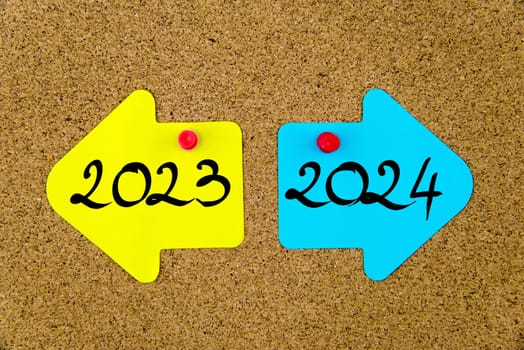 Blank yellow and blue paper notes in shape of opposite arrows pinned on cork board with thumbtacks, copy space available