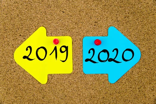 Blank yellow and blue paper notes in shape of opposite arrows pinned on cork board with thumbtacks, copy space available