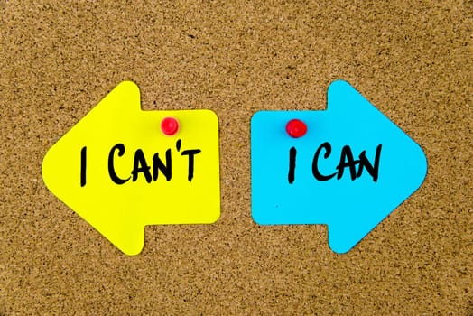 Blank yellow and blue paper notes in shape of opposite arrows pinned on cork board with thumbtacks, copy space available