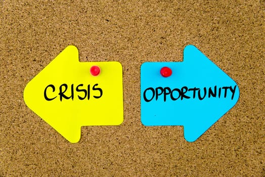 Blank yellow and blue paper notes in shape of opposite arrows pinned on cork board with thumbtacks, copy space available
