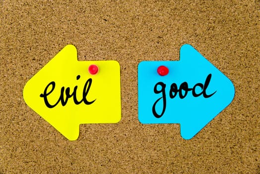 Blank yellow and blue paper notes in shape of opposite arrows pinned on cork board with thumbtacks, copy space available