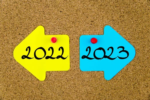 Blank yellow and blue paper notes in shape of opposite arrows pinned on cork board with thumbtacks, copy space available