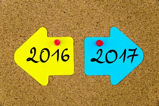 Blank yellow and blue paper notes in shape of opposite arrows pinned on cork board with thumbtacks, copy space available