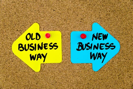 Blank yellow and blue paper notes in shape of opposite arrows pinned on cork board with thumbtacks, copy space available