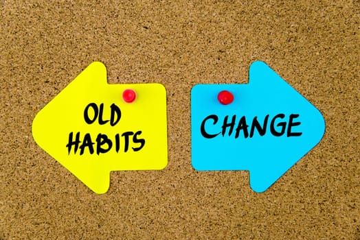Blank yellow and blue paper notes in shape of opposite arrows pinned on cork board with thumbtacks, copy space available