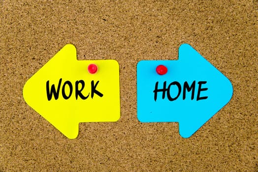 Blank yellow and blue paper notes in shape of opposite arrows pinned on cork board with thumbtacks, copy space available