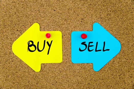 Blank yellow and blue paper notes in shape of opposite arrows pinned on cork board with thumbtacks, copy space available