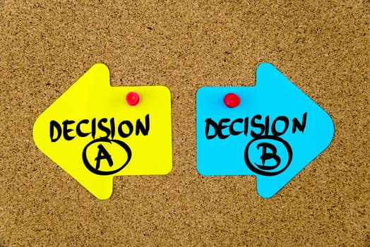 Blank yellow and blue paper notes in shape of opposite arrows pinned on cork board with thumbtacks, copy space available