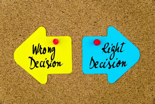 Blank yellow and blue paper notes in shape of opposite arrows pinned on cork board with thumbtacks, copy space available