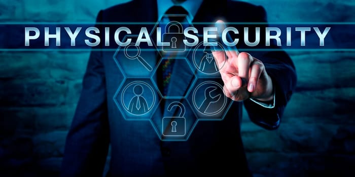 Intelligence officer is pushing PHYSICAL SECURITY on an interactive transparent control screen. Business metaphor and technology concept. Application icons with security tools arranged in a cycle.