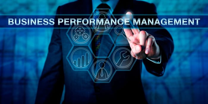 Manager is pressing BUSINESS PERFORMANCE MANAGEMENT on an interactive touch screen interface. Technology concept and business performance management metaphor with tool icons for analytic processes.