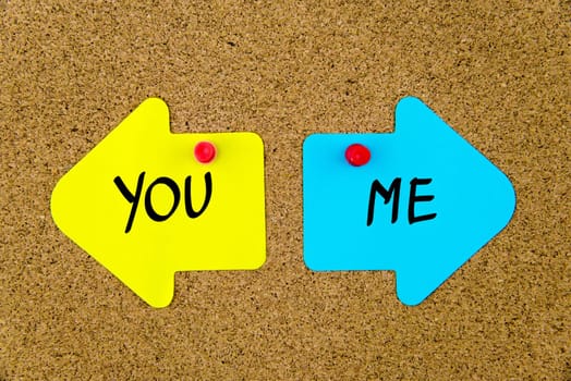 Blank yellow and blue paper notes in shape of opposite arrows pinned on cork board with thumbtacks, copy space available