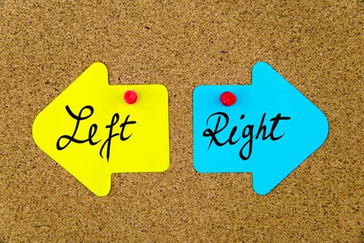 Blank yellow and blue paper notes in shape of opposite arrows pinned on cork board with thumbtacks, copy space available
