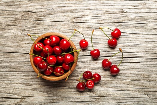 Fresh cherries in a bowl on wooden table.