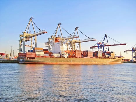 Hamburg, Germany - May 22, 2008: Hamburg harbor - panorama of the container terminal Burchardkai. Cranes loading ship, river Elbe in front.