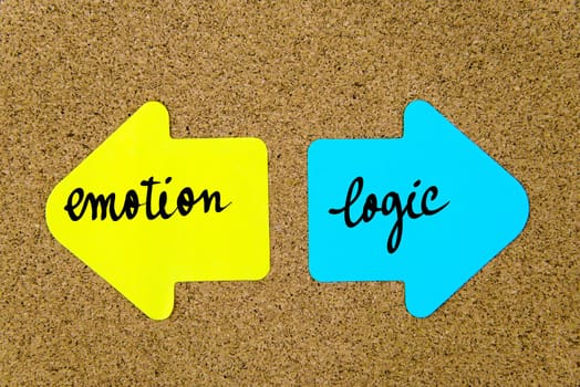Message Emotion versus Logic on yellow and blue paper notes as opposite arrows pinned on cork board with thumbtacks. Choice conceptual image