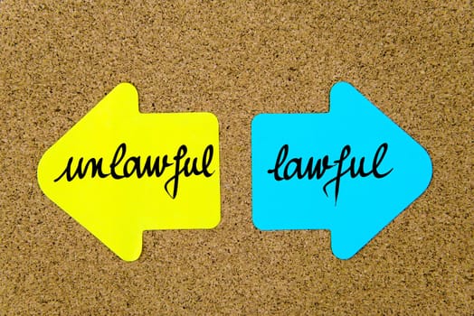 Message Unlawful versus Lawful on yellow and blue paper notes as opposite arrows pinned on cork board with thumbtacks. Choice conceptual image
