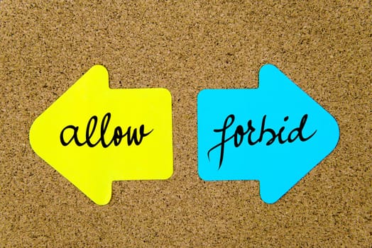 Message Allow versus Forbid on yellow and blue paper notes as opposite arrows pinned on cork board with thumbtacks. Choice conceptual image